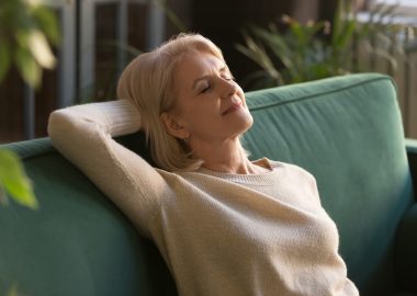 Happy beautiful mature woman rest on comfortable sofa in living room, see dreams visualize, peaceful exhausted elderly grandmother take break breathe air, relaxing on couch napping at home