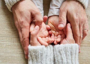 Seniors hands hold the hands of a child as a symbol of love and comfort